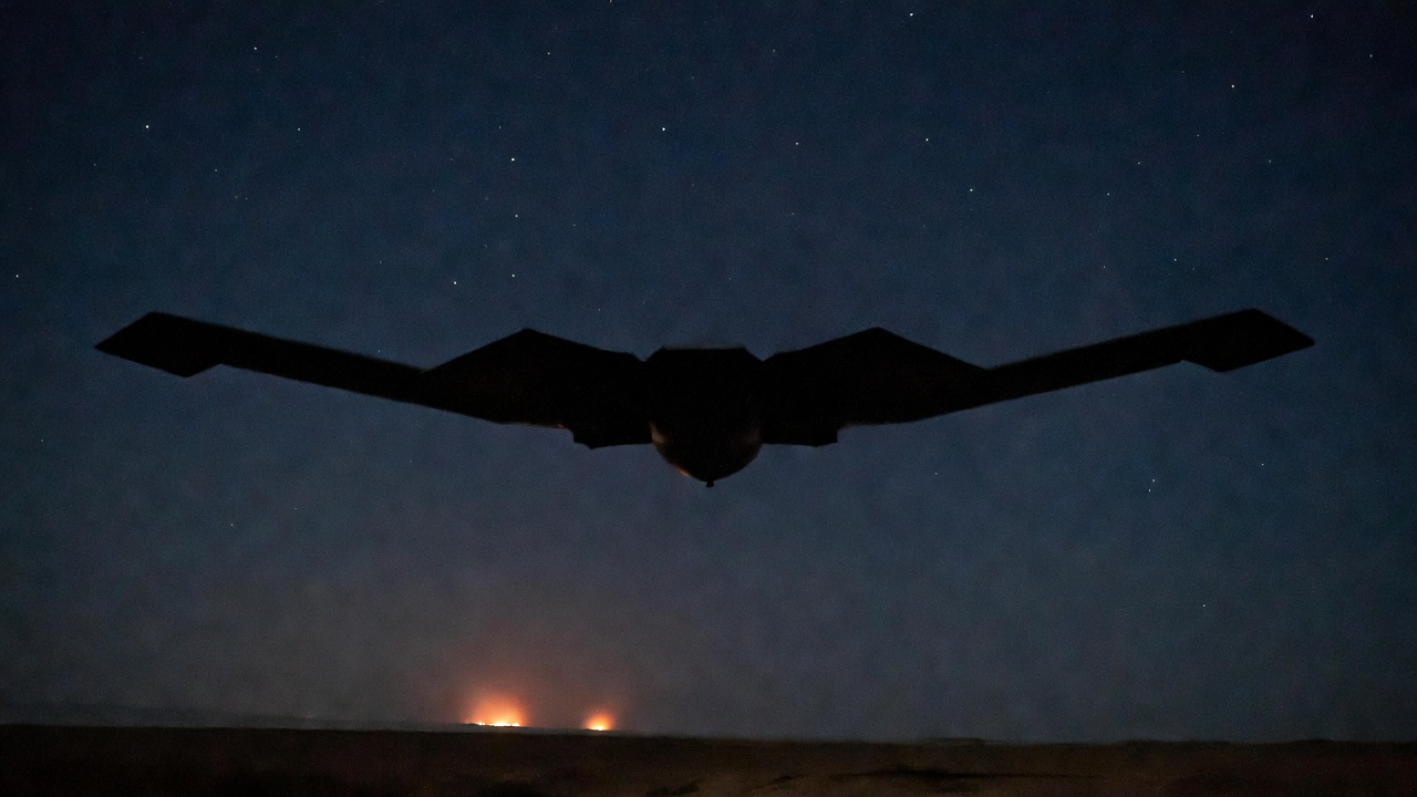 B-2 stealth bomber flying at night over burning targets
