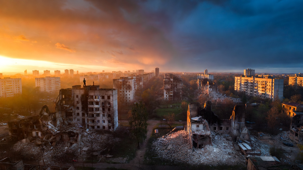 Destroyed Ukrainian city at sunset with lone figure standing on ruins