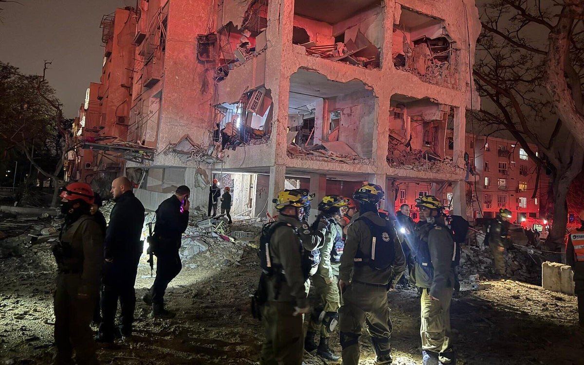 Destroyed building with rescue workers at night after missile strike