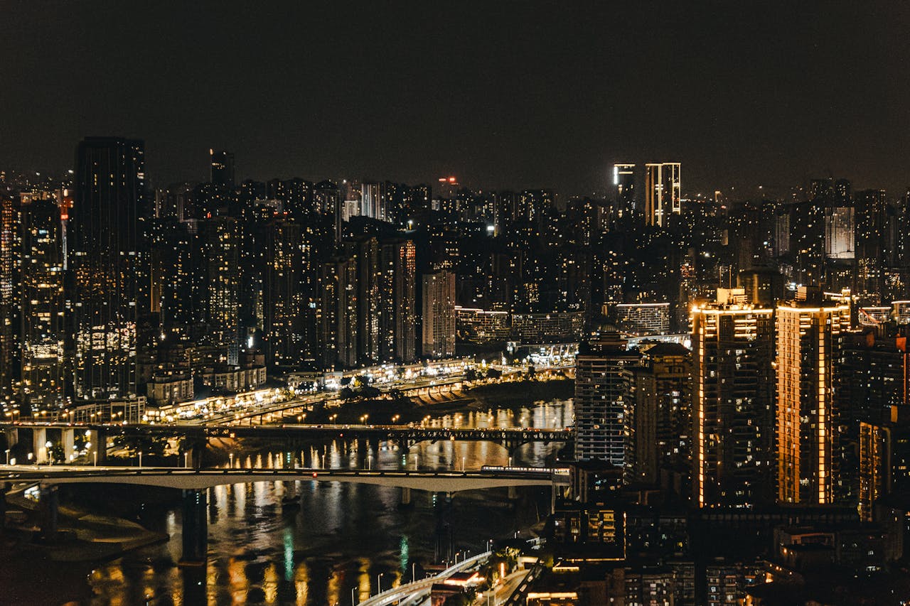 A breathtaking view of a cityscape at night with illuminated skyscrapers and reflections on the river.