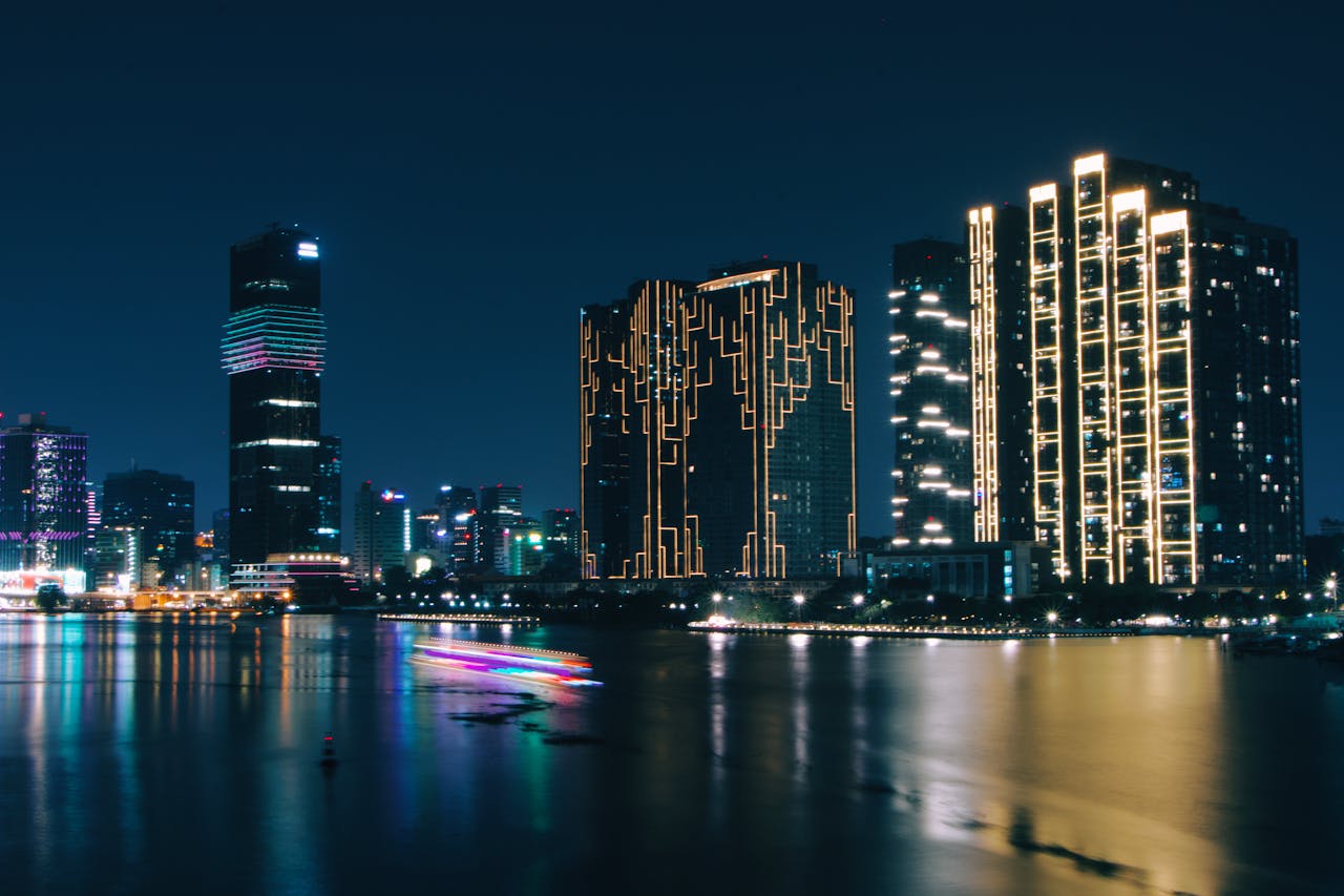 A stunning nighttime cityscape showcasing illuminated skyscrapers reflecting on calm waters.