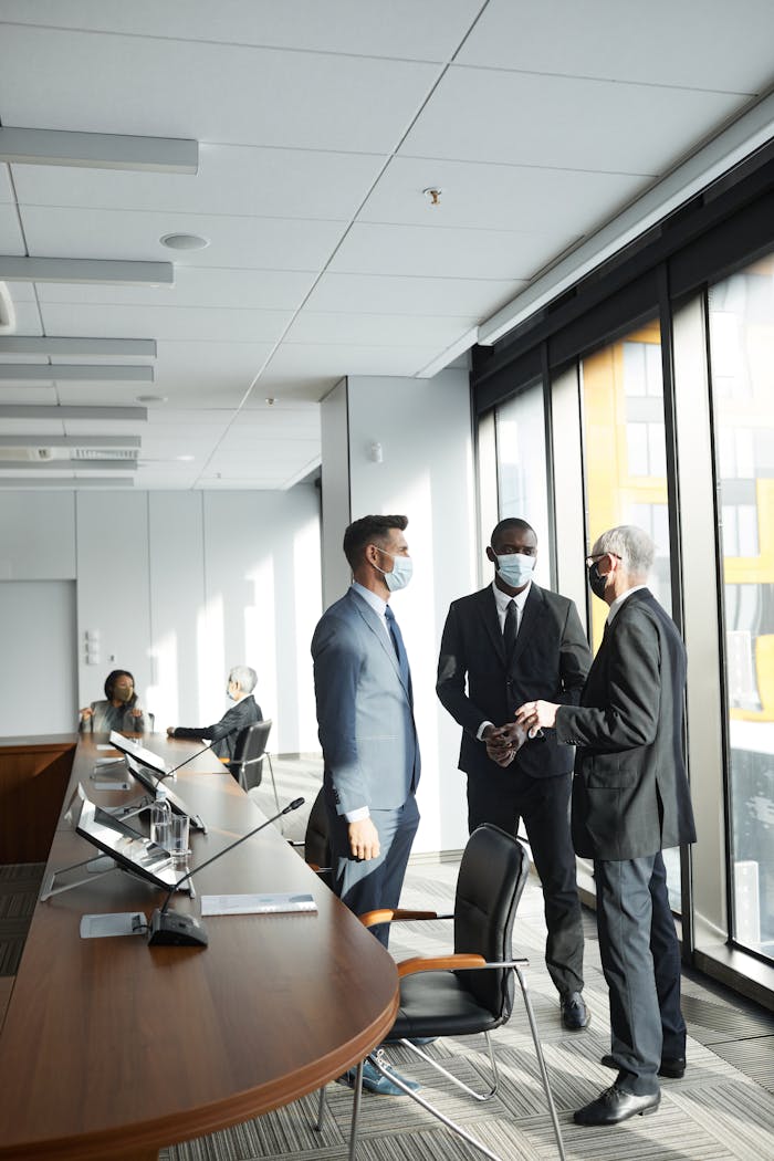 Professionals discussing in the office while wearing face masks for safety.