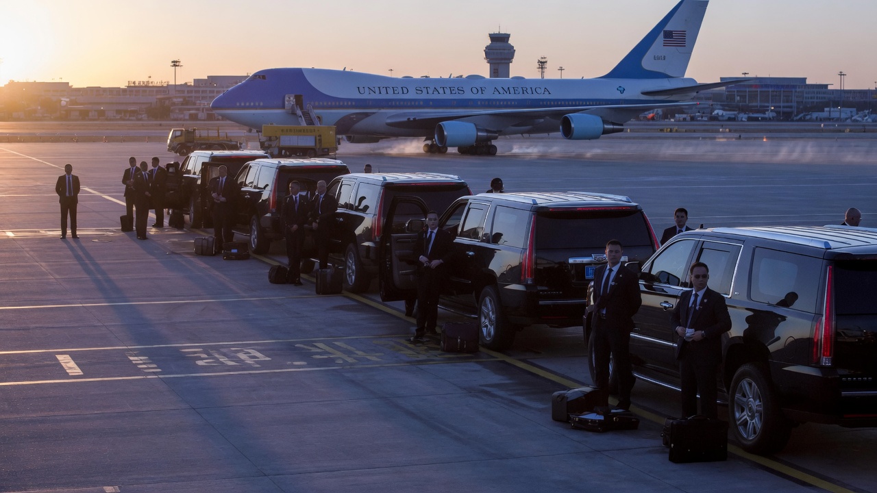 An American CEO delegation disembarking in Beijing — Apple, Tesla, and Nvidia executives accompanying the President as a demonstration of economic gravity.